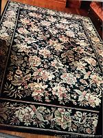 Full view of the 9x12 area rug showing floral and leaf pattern on black background with border design.