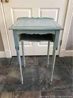 Frontal angled view of the painted bedside accent table showing the legs, apron, and part of the top surface.