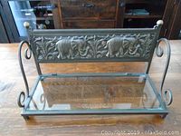 Full view of metal and glass shelf showing the clear glass base and metal sides with scroll accents.