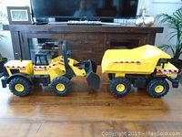 Both Tonka construction toys placed side by side on wooden floor, showing overall size and appearance.
