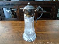 Front view of the vintage glass pitcher with silver plated lid and handle.