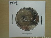 Photo of the front side of the 1978 Canadian one dollar coin showing a canoe with two figures and the date 1978.