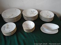 Full display of stacked dinner plates, salad plates, bowls, and grave dishes on tablecloth showing overall set.
