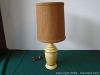 Full view of the vintage table lamp showing the yellow ceramic base and burlap lampshade with power cord.