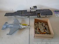 Photo showing the large aircraft carrier, jet, and a box of loose Mega Bloks pieces.