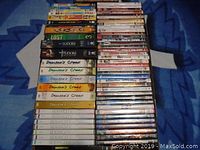 Photo shows stacked DVDs on a blue blanket with various titles visible including multiple Dawson's Creek sets, Lost, Sex and the City, and more.