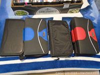 Four large CD/DVD holders placed closed on a blue and white surface, front view showing zippers and material textures.