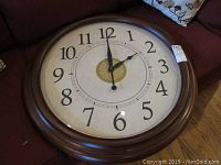 Full view of the Sligh wall clock showing the wood frame and clock face with numerals and gold center accent.