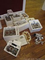 Overview of multiple Dept 56 boxed buildings and accessories on wooden floor, showing overall lot contents.