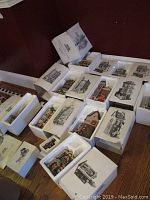 Full view of the Dept 56 Christmas in the City collection pieces in original boxes with styrofoam inserts on wood floor.