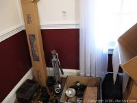 General view of lot showing General Electric vintage radio model 100, camera equipment and tripod, and boxes.