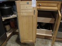 Wood kitchen cabinet drawer and door opened revealing stacked bowls and kitchen items.
