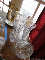 Wide shot showing multiple crystal vases, porcelain angel figurine, Norcrest fine china bowl, and porcelain vase on table