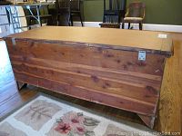 Back side view of wooden cedar chest showing natural wood finish and metal latch on corner.