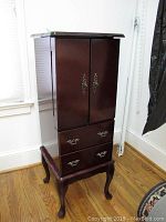 Full view of tall wooden jewelry stand with cabriole legs and two drawers at bottom.