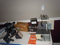 Overview of the lot with tools, testing instruments, cables, manuals, and boxes against a beige wall