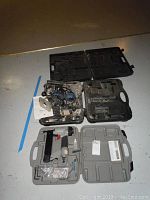 Overview of all three items: Porter Cable stapler in grey case, Strategy spin saw in black case, additional black case.