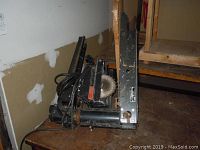 Side view of Sears 9 inch radial arm saw showing its blade and radial arm on the floor.