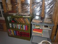 Two bookshelves filled with various vintage books, some stacked on top and a few vinyl records on top of the green shelf