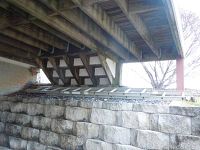 20 foot aluminum extension ladder placed under a back deck horizontally on rocks and wooden ledge.