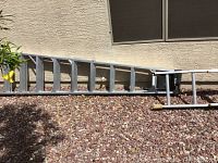 Full length view of aluminum ladder laid on ground showing structure and length.