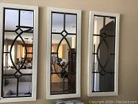Front view of the three matching rectangular mirrors hanging on the wall, showing white wooden frames and metal decorative pattern on the mirror glass