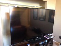 Front view of Sharp Aquos TV on stand with remote and discs
