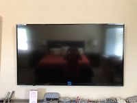 Front view of wall-mounted Sharp TV showing screen and bezel
