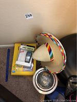 Photo showing the lot items on floor: two sombreros, Rosetta Stone Spanish CD set, Garmin eTrex Legend GPS in box, and a small globe in metal frame.