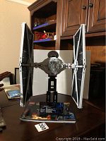 Full frontal image of the assembled LEGO TIE Ln Starfighter model on display stand on a wooden table with furniture background.