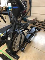 Side view of the elliptical showing foot pedals, frame and console