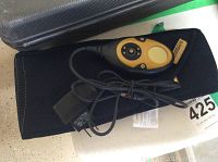 Photo showing the black neoprene abdominal strap with attached Slendertone control remote and attached power adapter charger.
