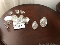 Wide view of assorted Swarovski crystal figurines arranged on a wooden surface showing swans, hedgehogs, and other small pieces.