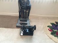 Photo showing Hoover upright vacuum cleaner and vintage Spartan sewing machine on floor