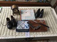 Full lot image showing all items on wicker table including shoes, handkerchiefs, wooden tray, straight razor, and clock.