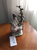 Front view of porcelain figurine with seated girl, tree and bird on base