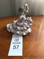 Front view of figurine on wooden tabletop with auction tag