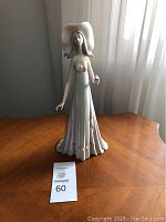 Full view of Lladro The Debutante porcelain figurine on wooden table near window