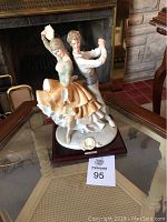 Photo of Spanish dancing couple ceramic sculpture on glass table in front of fireplace for lot identification.