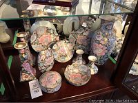 Photo showing the full assortment of Toyo cloisonné china items with golden peony floral patterns including vases, plates, trinket box, bowl, and candle holders arranged on a display surface.