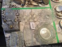 Top down view showing arranged glassware and silver accented cruet set on lace table cloth.