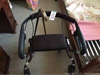 Top view photo showing black walker with padded handles, seat and wheels.