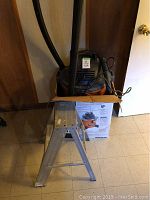 Photo front view showing the ShopVac and the metal stepladder inside the original ShopVac box.
