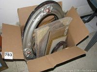 Box containing seven smaller rectangular frames in varying conditions, some wrapped in bubble wrap, plus one large oval frame with decorative silver and black finish.