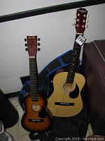 Full image showing both Mark II and Carlo Rebellion guitars leaning against wall with guitar cases