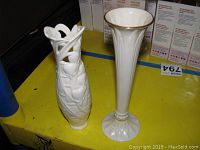 Both Lenox porcelain vases showing size and design contrast, placed on yellow surface with boxes in background