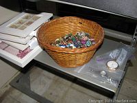 Basket filled with assorted earrings next to Elgin pocket watch and three framed shell decor art pieces stacked