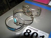 Three silver bracelets positioned together showing differing designs and stones.