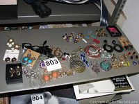 Top view of dozens of assorted costume jewelry earrings arranged on a shelf.