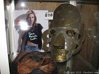 Photo showing autographed Sarah Michelle Gellar photo along with wood and metal masks in display.